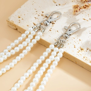 Detailed view of triple-strand pearl trousers chain with silver lobster clasps on stone