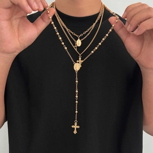 Détail de colliers superposés dorés avec pendentifs croix et Vierge Marie sur modèle