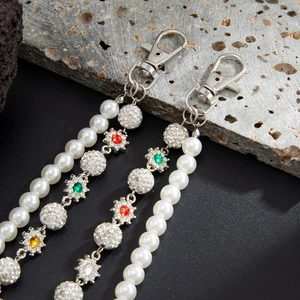 Close-up of pearl trousers chain with colorful rhinestone flowers and diamond balls