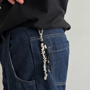 Détail du porte-clés perlé avec perles argentées sur un jean en denim bleu foncé