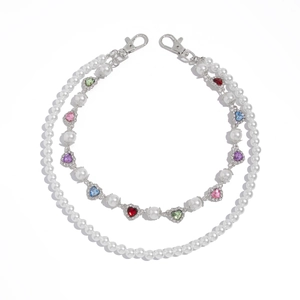 Detailed view of layered pearl chain with colorful rhinestone heart charms and silver clasps