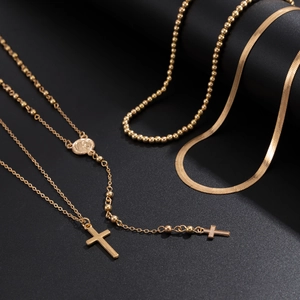 Gold cross pendant necklace and flat snake chain set on professional black background
