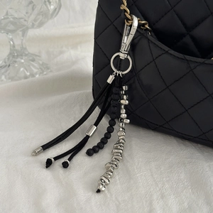Vue détaillée du bijou de sac à pompon noir avec des perles et un fermoir argenté