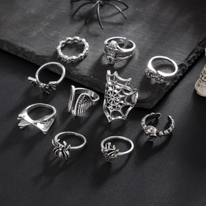 10-piece set of retro silver gothic skull and spider rings on dark stone background