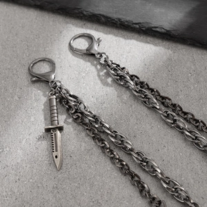 Macro view of industrial punk trousers chain featuring a detailed metal dagger pendant