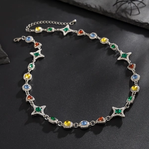 Detalle de collar con gemas multicolores y cadena plateada sobre fondo de piedra oscura