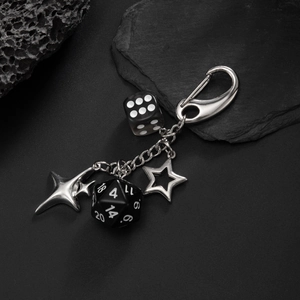 Hip-hop style metal keychain with black resin dice and silver star pendants on dark rock