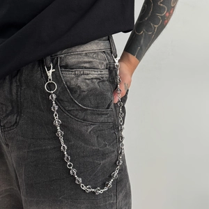 Punk style silver metal wallet chain with embossed spherical links on denim jeans