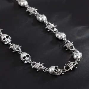 Close-up of punk style trousers chain with silver skull charms and barbed wire links