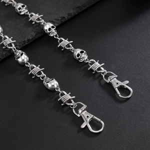 Detail of gothic pants chain with silver skull charms and barbed wire links