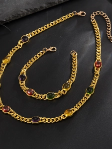 Detail of gold curb chain jewelry set with vibrant oval red and green gemstones