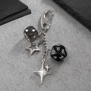Retro pentagram star and dice keychain with silver alloy clasp on stone background