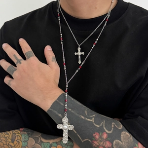 Double-layered silver necklace with red beads and cross pendants on tattooed male model