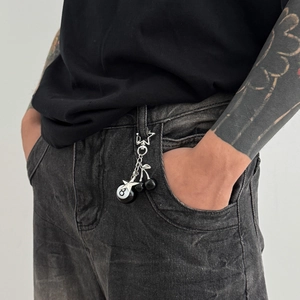 Detail of punk style keychain with billiard 8-ball, star and black cherry on denim jeans