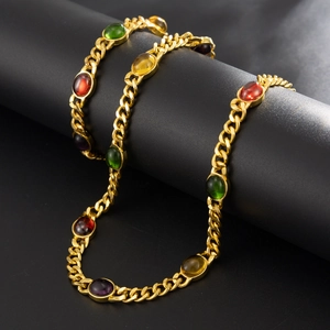 Golden Cuban link necklace with colorful gemstones displayed on a minimalist cylinder