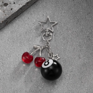 Trendy billiards number 8 and cherry keychain with star metal clasp on stone background