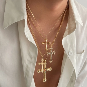 Gros plan sur trois colliers croix dorés avec strass et pendentifs de style vintage