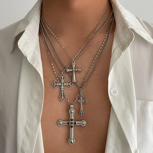 Détail de colliers superposés en métal argenté avec pendentifs croix de style gothique
