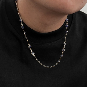 Dettaglio di una collana occhio di Allah dorata con perline in smalto blu su modella