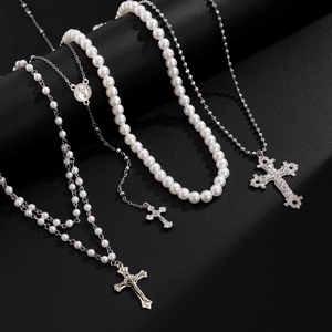 Detail van gelaagde zilveren kettingen met parels en religieuze kruis hangers