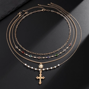 Gold layered necklace with pearl chain, crystal accents and cross pendant on black stone