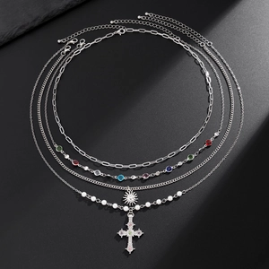 Macro shot of a 4-layer silver necklace set with a cross pendant and pearls on stone