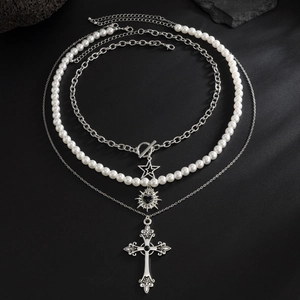 Men's layered necklace set with pearls and silver cross pendant on a black stone surface