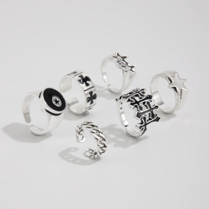 Detailed flat lay of silver rings set with cross and star motifs on white background