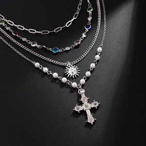 Close-up of layered necklace with cross pendant, colorful crystals and pearl chain