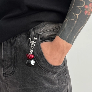 Street style keychain with star buckle, red cherry bead and 8-ball charm on gray jeans