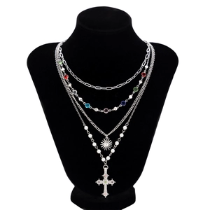Dettaglio collana argentata a strati con ciondolo a sole, perle e croce con cristalli colorati