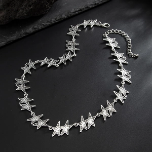 Close-up of silver hollow star link necklace on black stone texture background