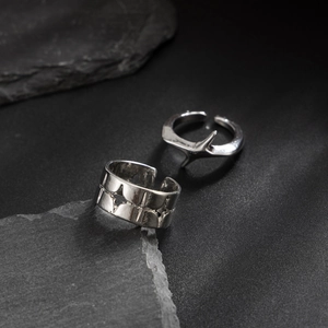 Macro view of silver adjustable punk rings with star patterns and spike detail on slate