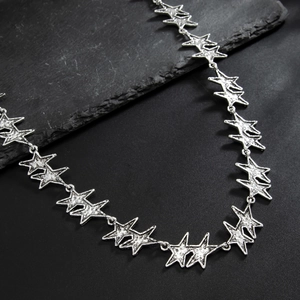 Detailed shot of silver textured star link necklace on black stone surface