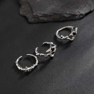 Detail shot of three silver thorn-style rings with black gems on a natural stone base