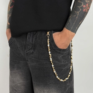 Detail of hip hop style pants chain with gold metallic beads and white faux pearls