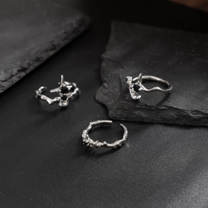 Gothic silver alloy ring set with black stones and cross details on dark rock