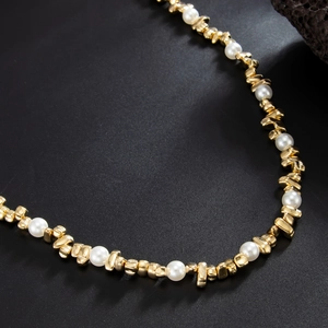 Close-up of irregular gold beads and white pearls on a hip-hop style jean chain