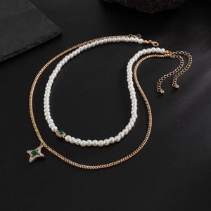 Detail einer Goldkette mit Perlenhalskette, Sternanhänger und grünem Edelstein