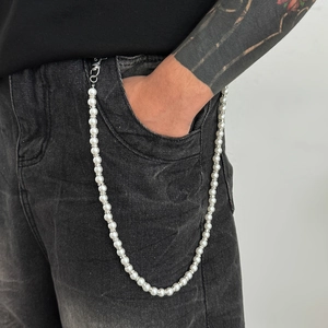 Détail de la chaîne de pantalon en perles avec séparateurs en strass sur jean noir