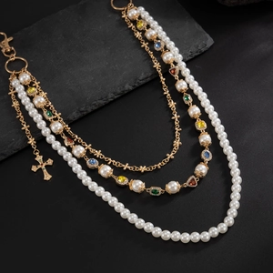 Close-up of multilayer gold necklace with colorful crystals, pearls and cross pendant
