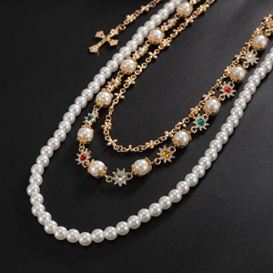 Detail of multilayer chain with colorful rhinestones, pearls and a golden cross pendant