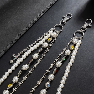 Detail of hip hop pearl chain with cross pendant and colorful zircon on dark rock