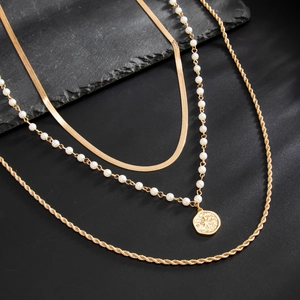 Three-piece layered gold necklace set with pearls, snake chain, and coin pendant