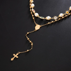 Close-up of layered gold necklace with pearls, sun pendant, and religious cross charm