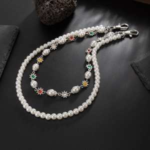 Détail d'une chaîne de jean à double rangée de perles avec étoiles en strass colorés