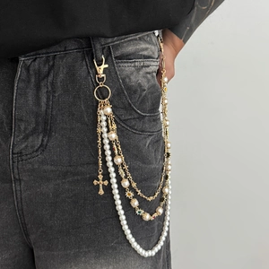 Multilayered pearl pants chain with cross and flower pendants on denim jeans