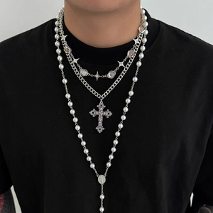 Detail of layered men's silver cross necklaces and pearl strands worn on a black shirt