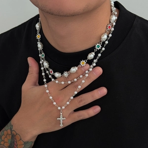 Dettaglio collana a strati con perle finte, gemme colorate e pendente a croce con strass