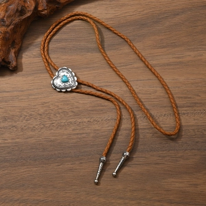 Détail macro du bolo tie cœur turquoise avec boucle gravée argent sur bois rustique